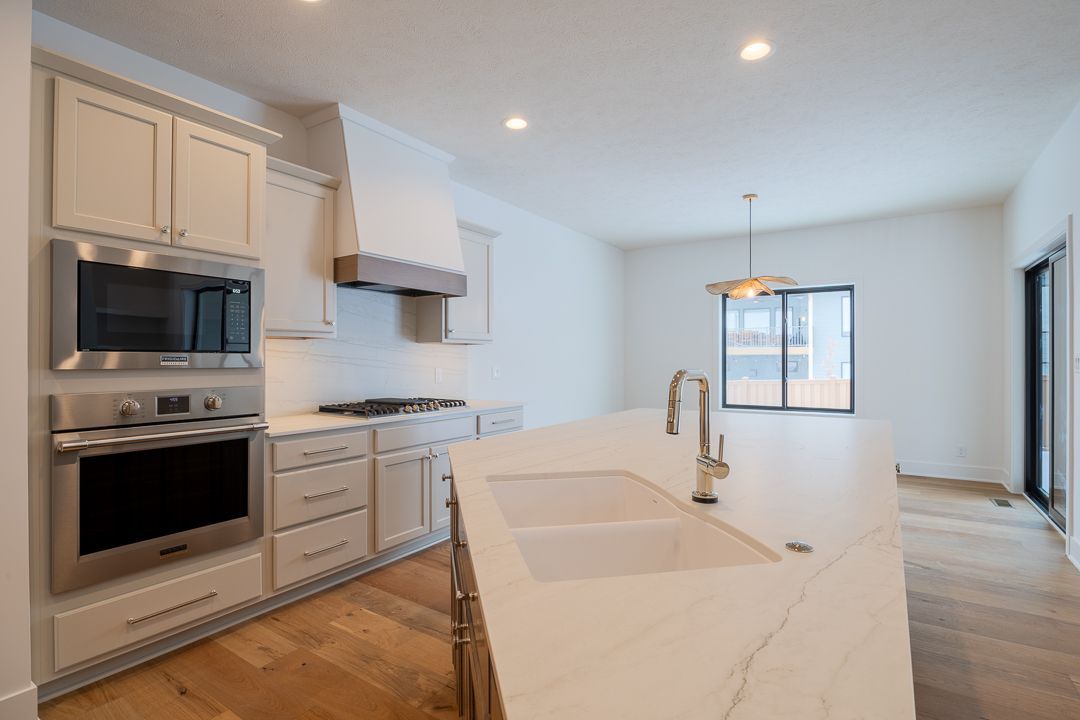 Kitchen with white cabinets, stainless steel appliances, and a marble island with a sink.