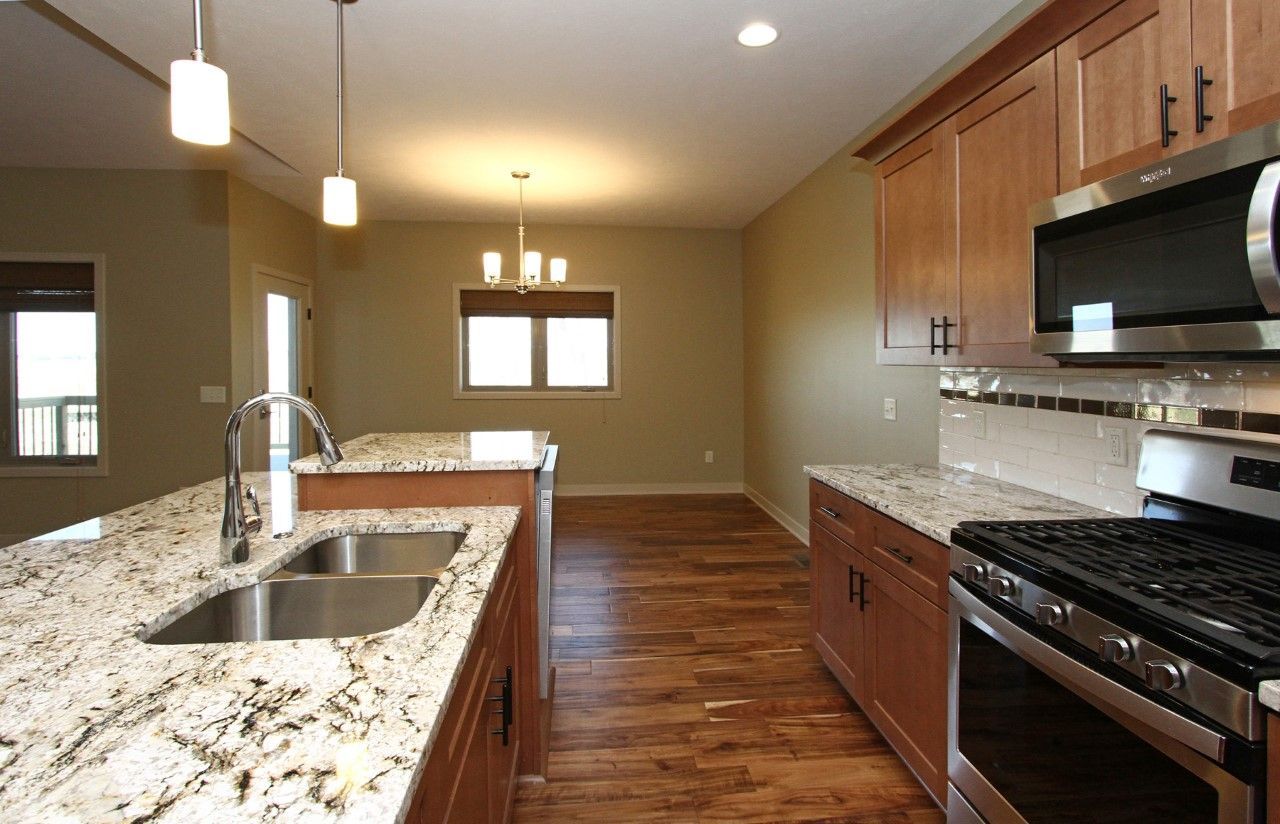 Modern kitchen with granite countertops, stainless steel appliances, and wood flooring.