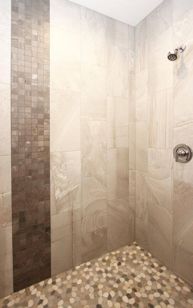 Tiled shower with pebble floor, vertical brown mosaic accent. Silver shower head and faucet.