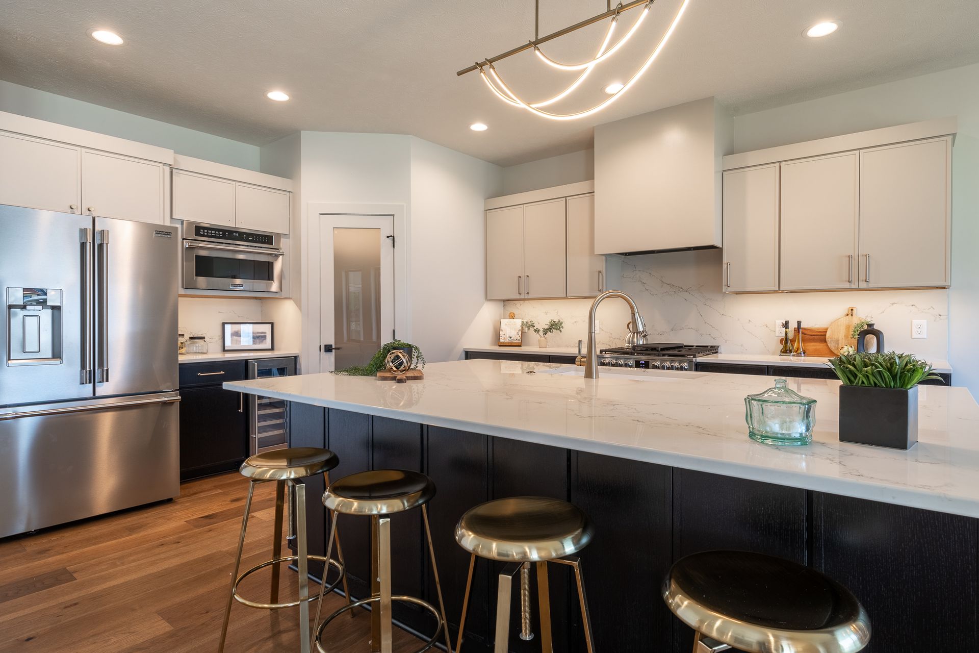 Modern kitchen with black and white cabinets, stainless steel appliances, and a marble countertop island.