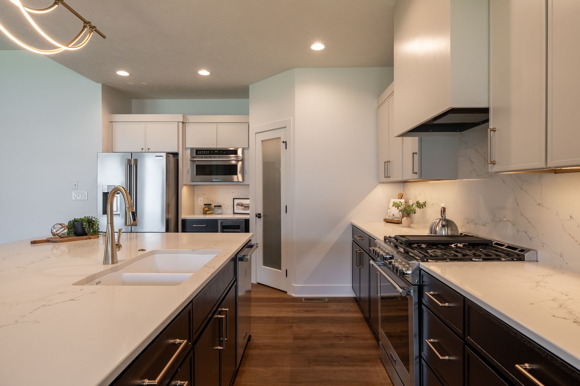Modern kitchen with white countertops, dark cabinets, stainless steel appliances, and a gas range.