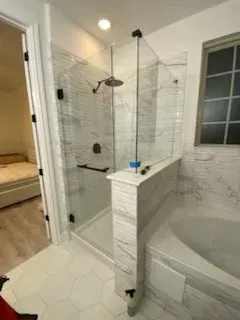 A modern bathroom featuring a glass-enclosed shower with marble-style tiles and a separate adjacent soaking tub.