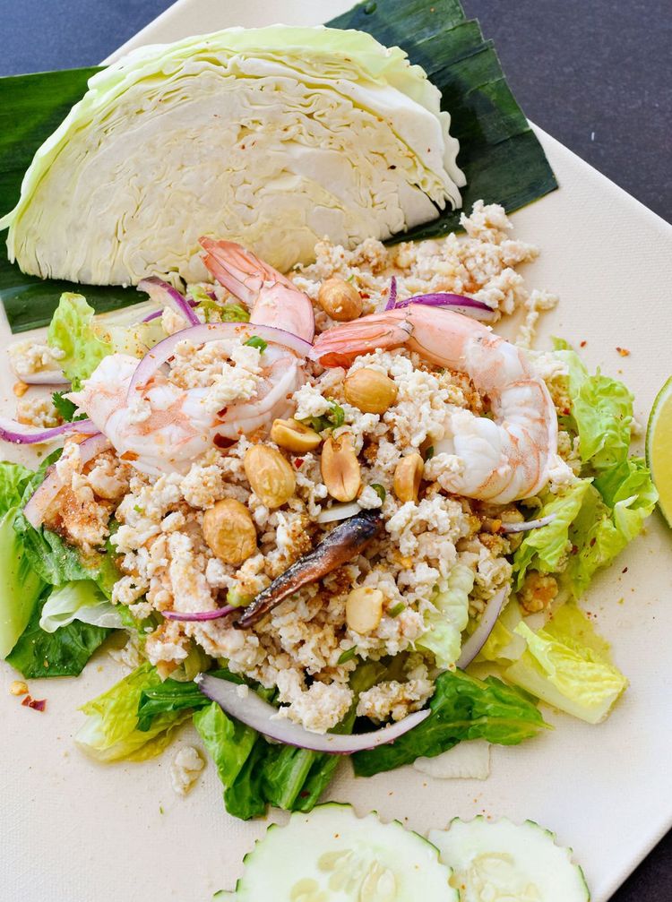 a white plate topped with rice , shrimp , lettuce , onions and cucumbers .