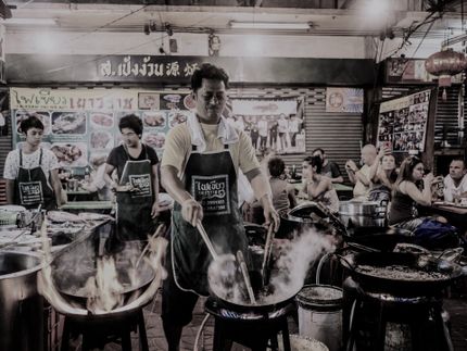 a man is cooking food in a wok in a restaurant .
