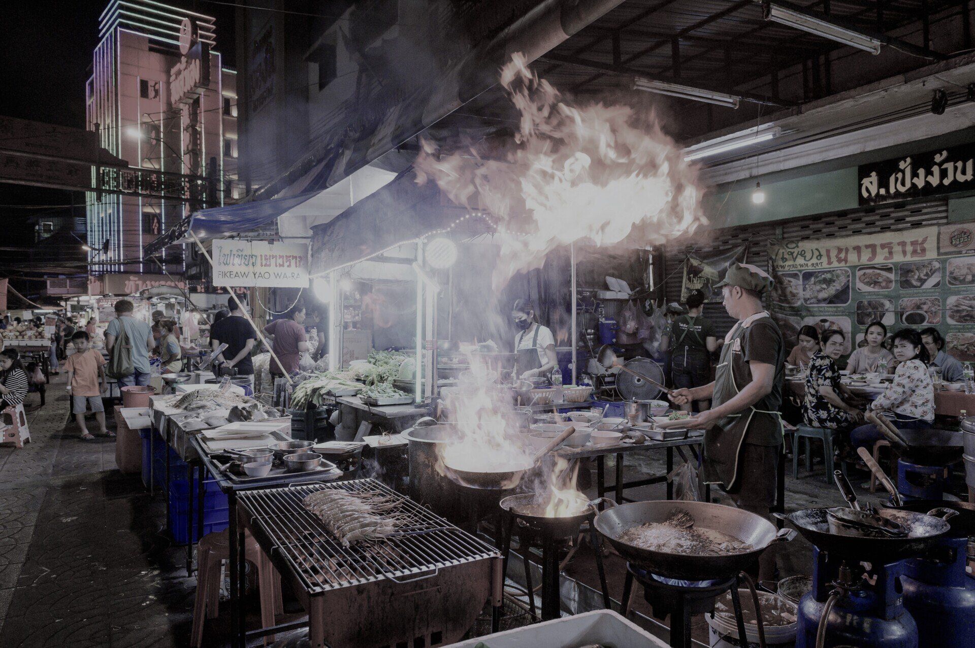 a man is cooking food in a restaurant at night .