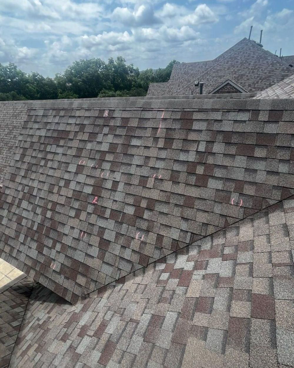 Brown and gray shingled roof under a cloudy sky.