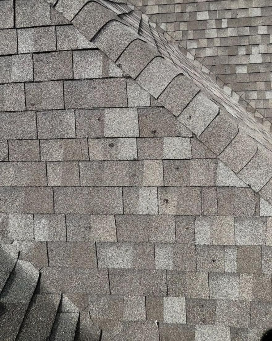 Gray asphalt shingles on a roof, angled at the peak, showing texture and layering.