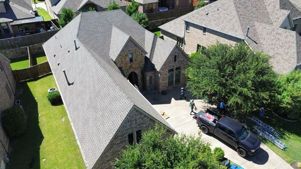 Aerial view of a home with a truck parked in the driveway; roof repair in progress.