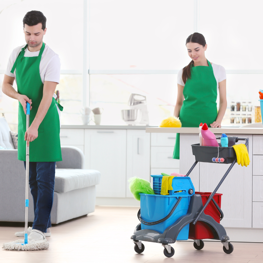 Two people cleaning an indoor space. One mops floor. The other stands by a cleaning cart in the kitchen.