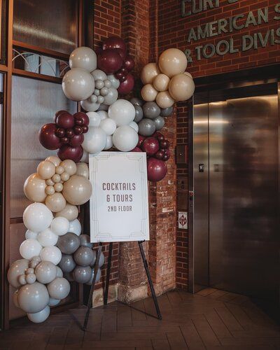 a bunch of balloons are hanging from a sign in front of a building