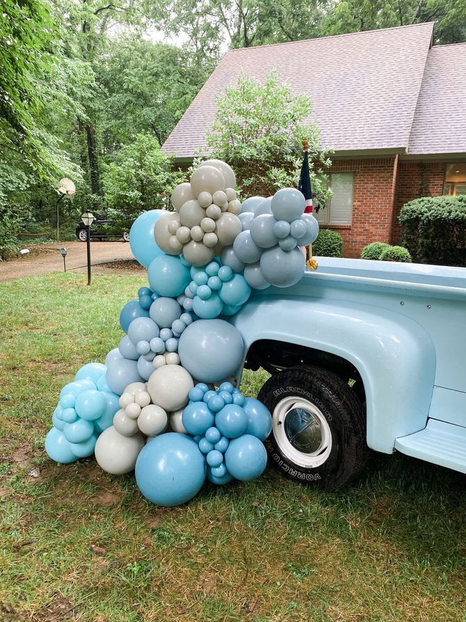 a blue truck is decorated with balloons in front of a house