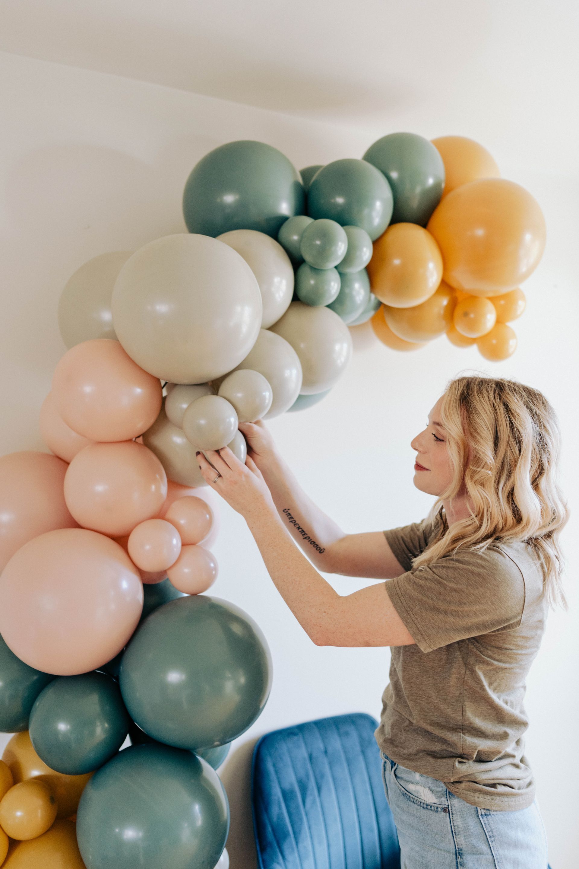 a woman is making a balloon arch in a room