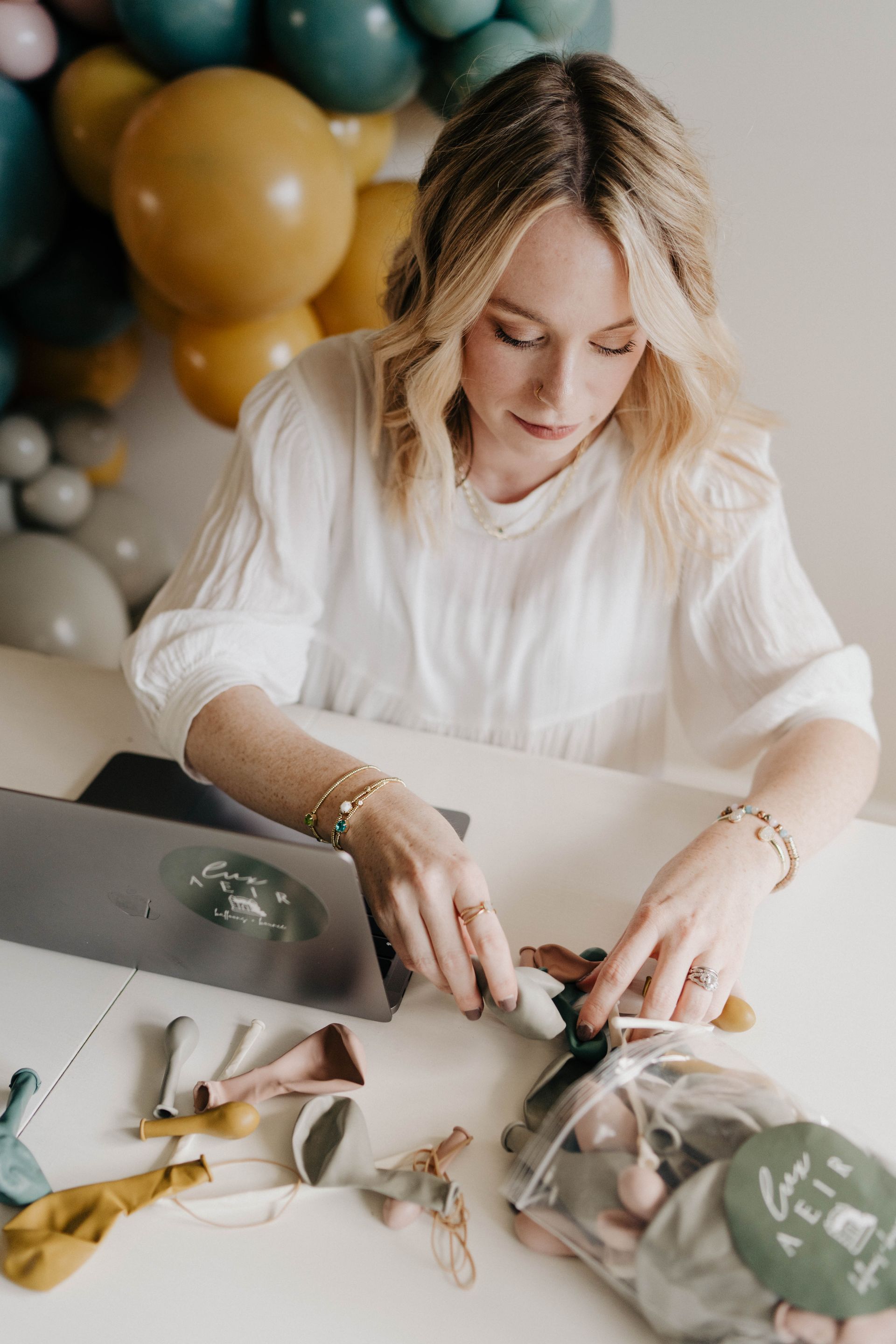 a woman is sitting at a table with balloons in the background