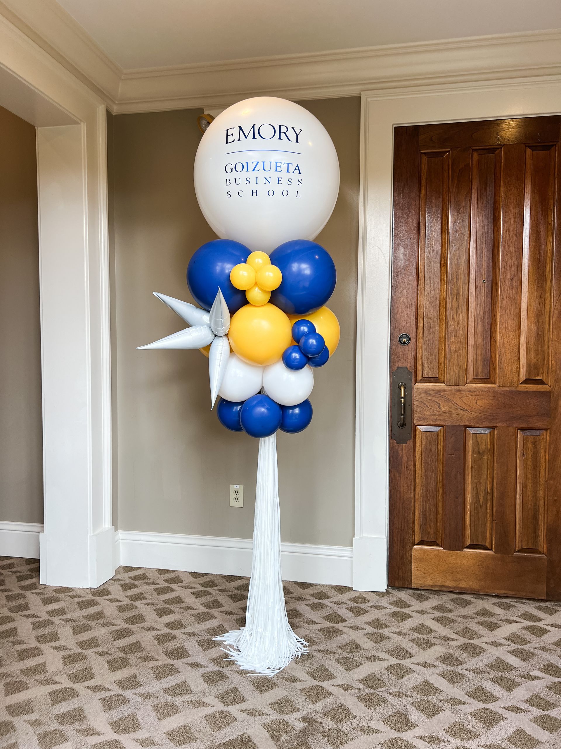 A bunch of balloons are sitting on top of a white pole in a room.