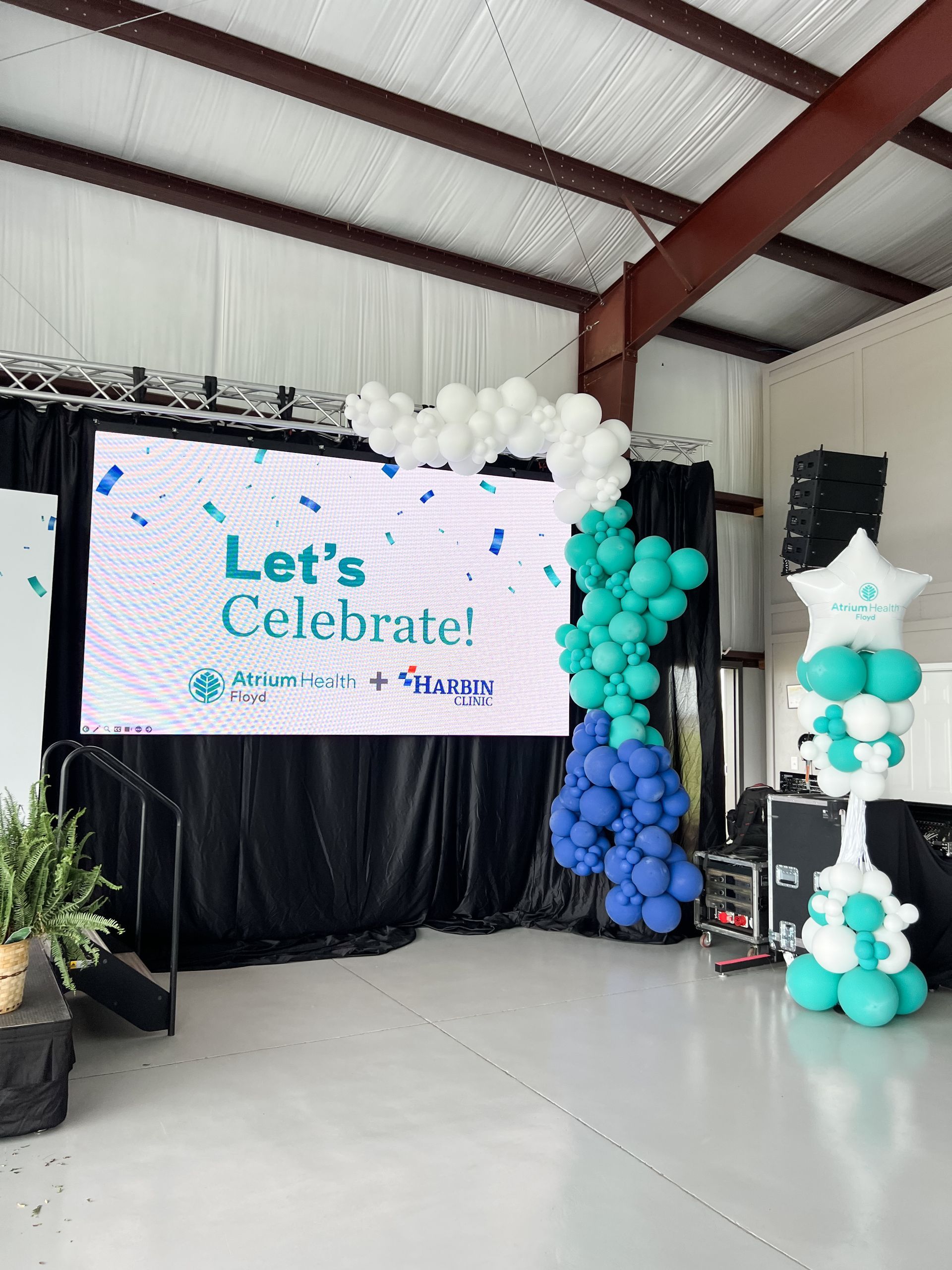 A stage with an organic balloon garland and a sign that says 