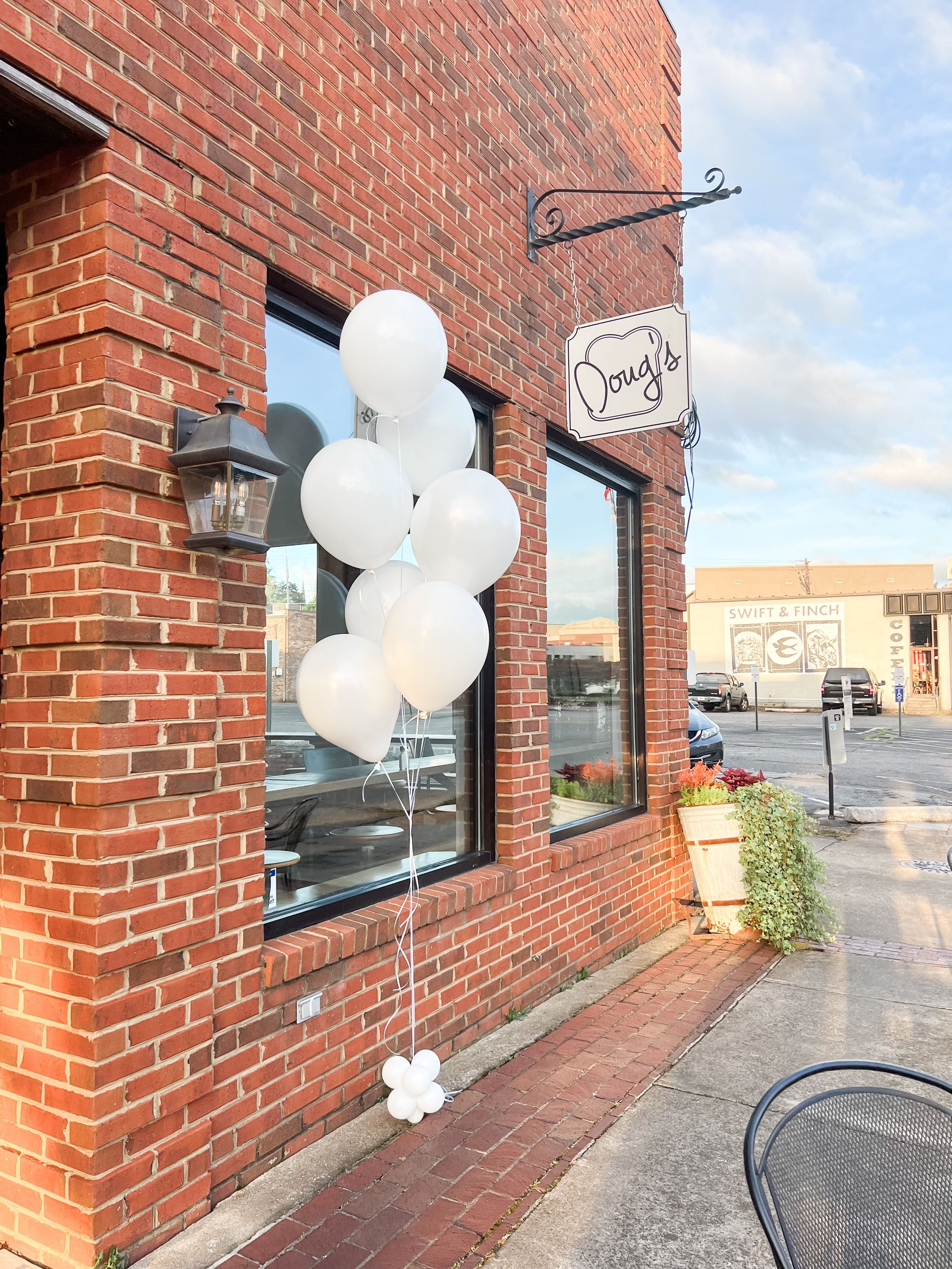 A bunch of white balloons are sitting outside of a brick building.