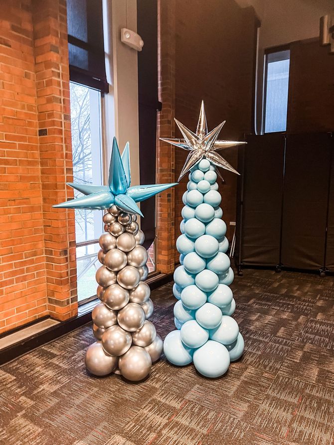 two christmas trees made out of balloons in a room