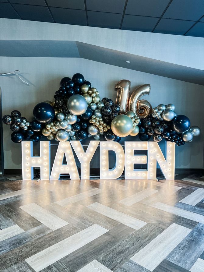 a large sign that says hayden is surrounded by balloons and lights
