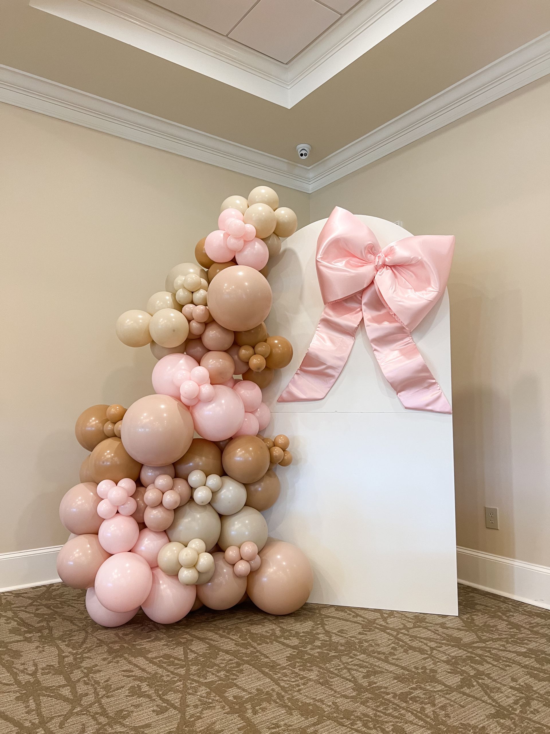 A room filled with balloons and a pink bow for a baby shower.