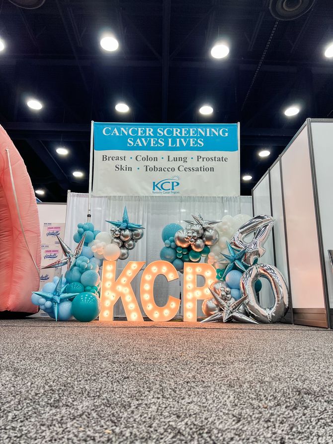 a sign that says cancer screening saves lives is surrounded by balloons