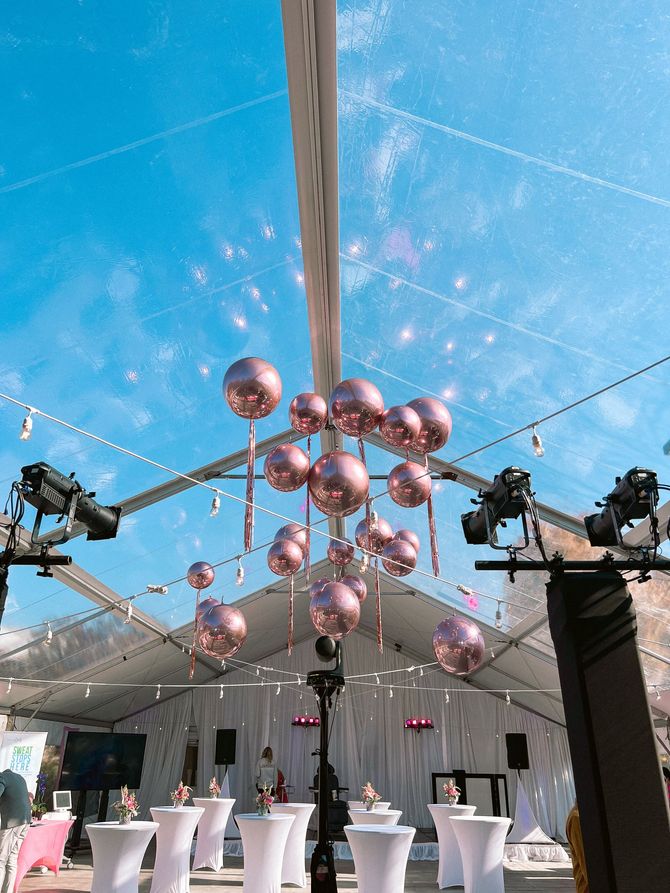 a tent with tables and balloons hanging from the ceiling