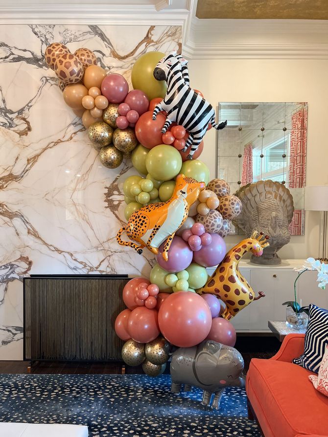 a bunch of balloons with animals on them are hanging on a wall in a living room