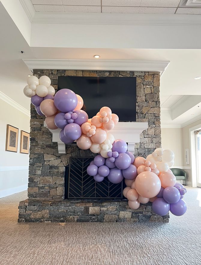 a balloon garland is hanging over a fireplace in a living room