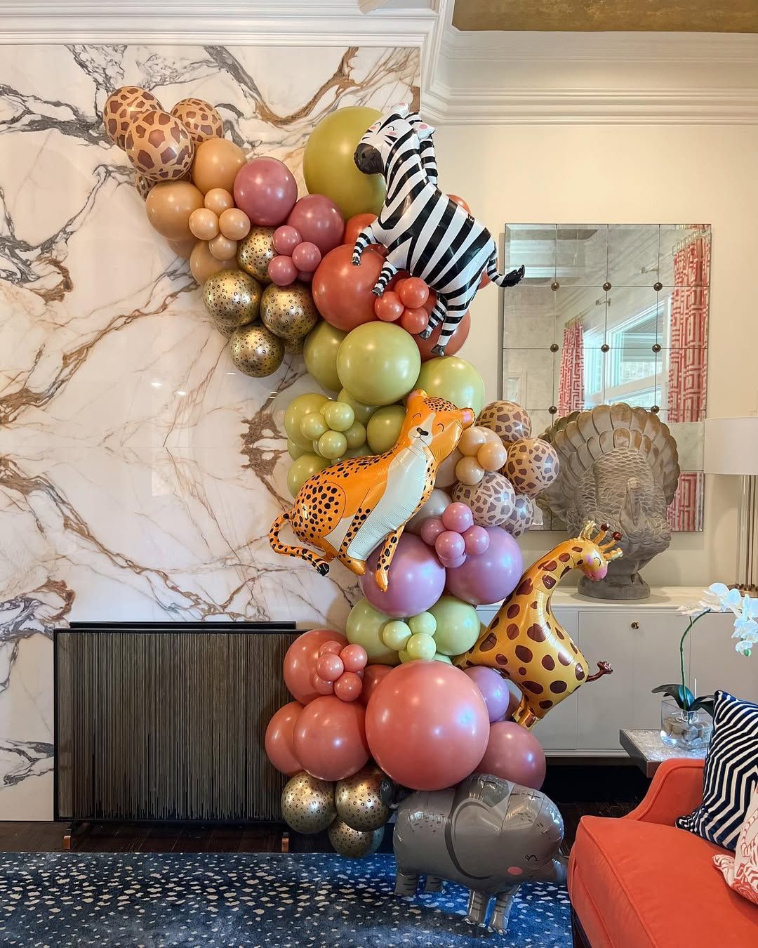 A colorful jungle-themed balloon garland featuring animal balloons like a zebra, cheetah, giraffe, and elephant.