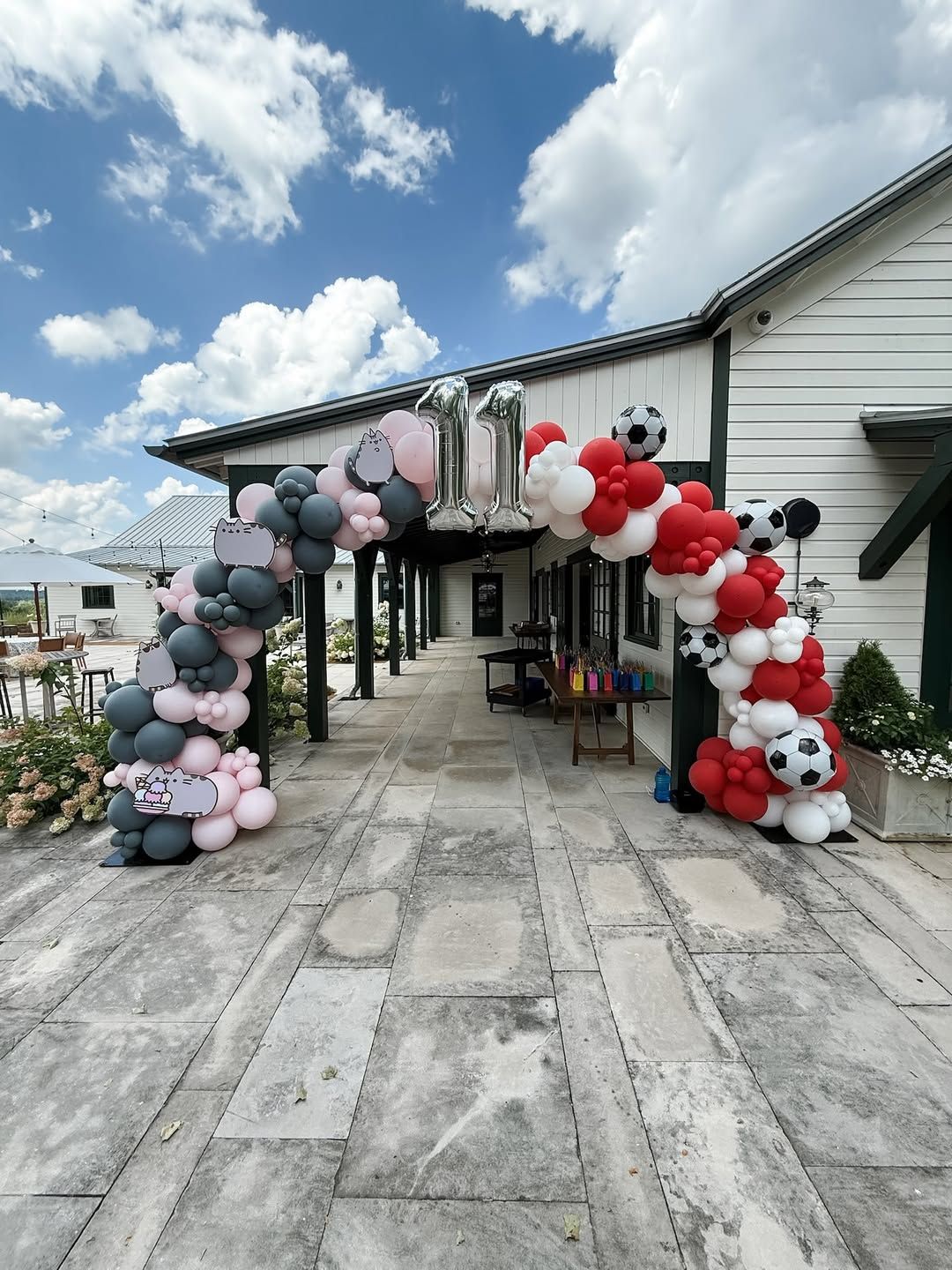 A balloon arch for an 11th birthday, featuring black, pink, red, and white balloons accented with soccer ball balloons.