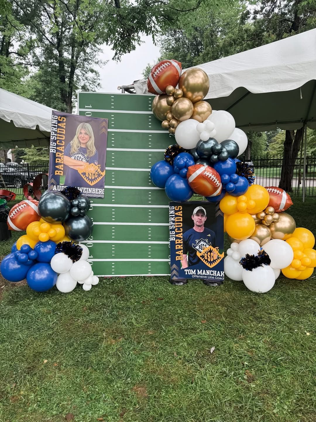 A football-themed party backdrop with a green field display, balloons, and posters for a Barracudas team event outdoors.