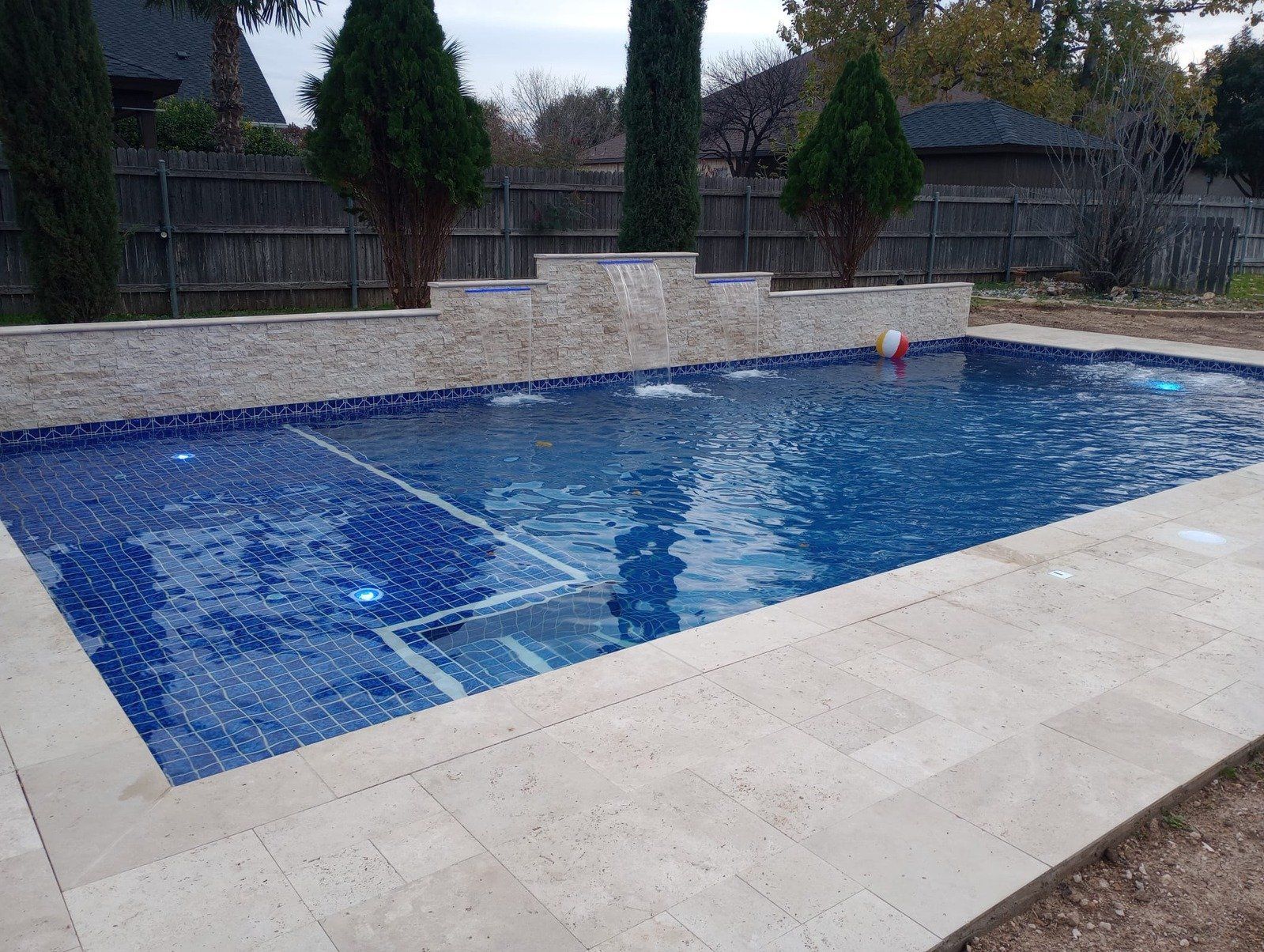 A large swimming pool with blue tiles and a waterfall