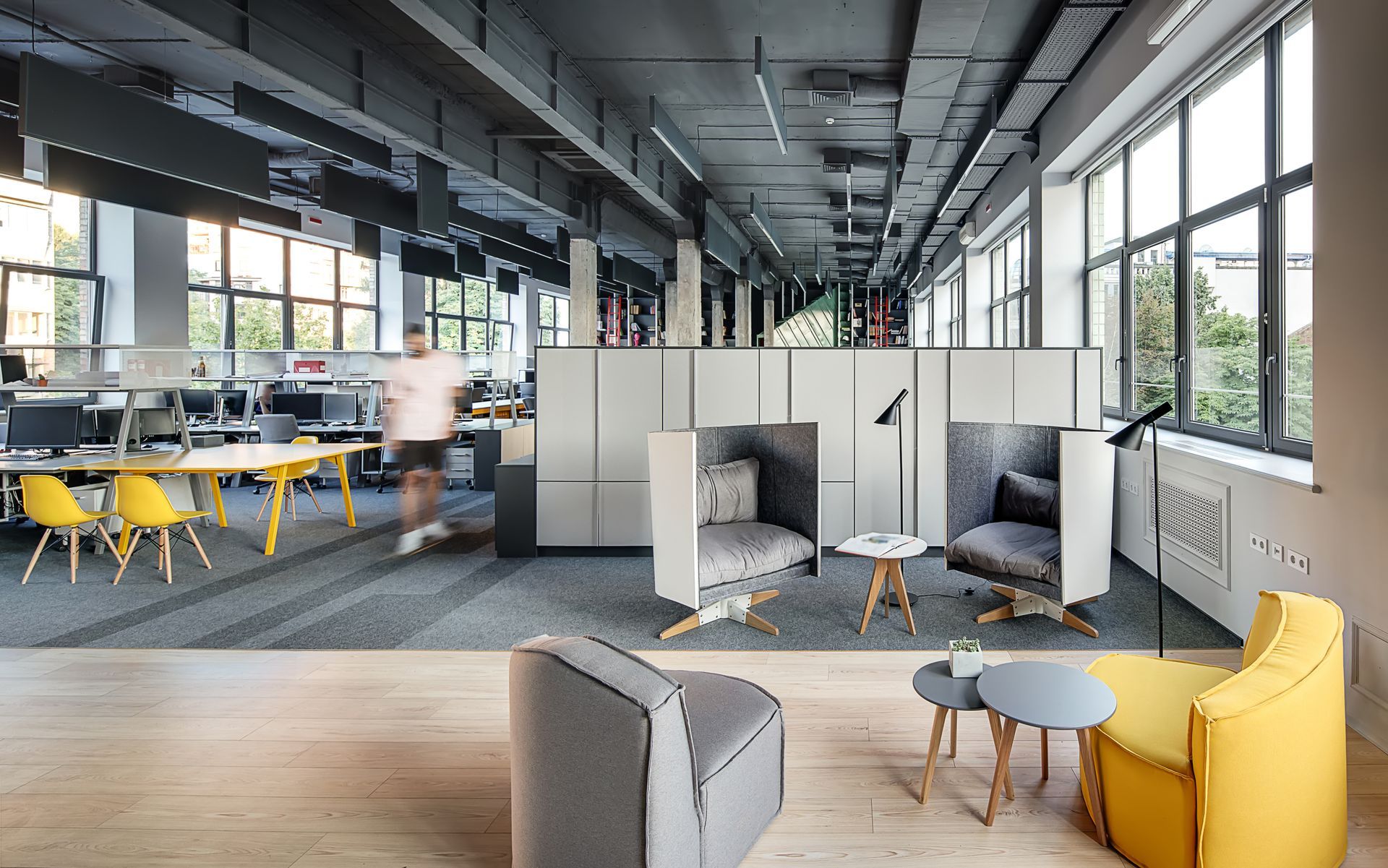 A blurred view of an office employee walking through a modern, loft office.