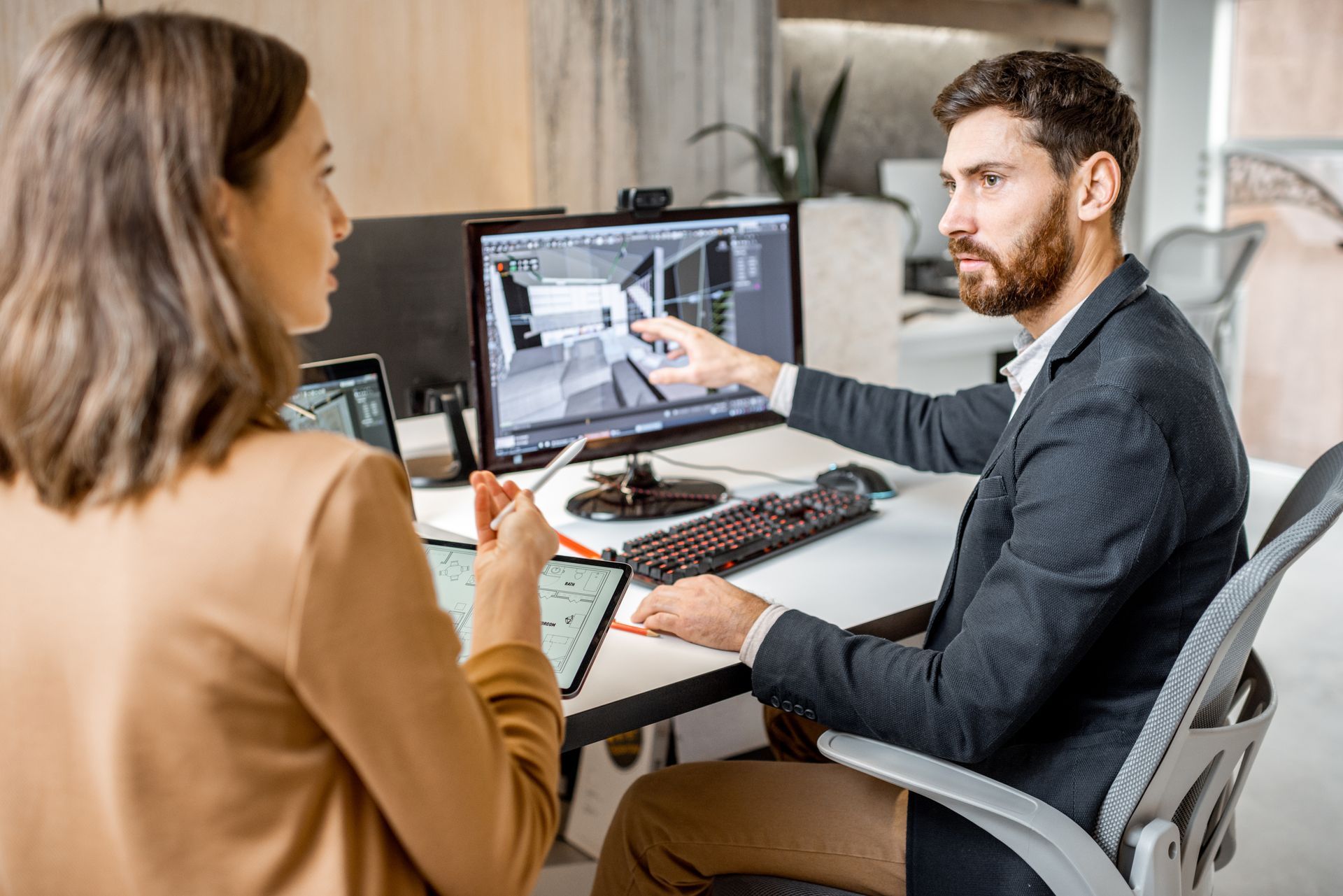 Two creative office employees are making interior designs on a computer and a digital tablet.