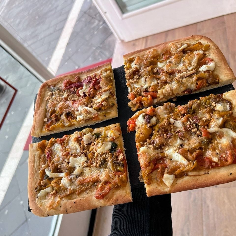 Quattro fette di pizza rettangolare con i condimenti sollevati.