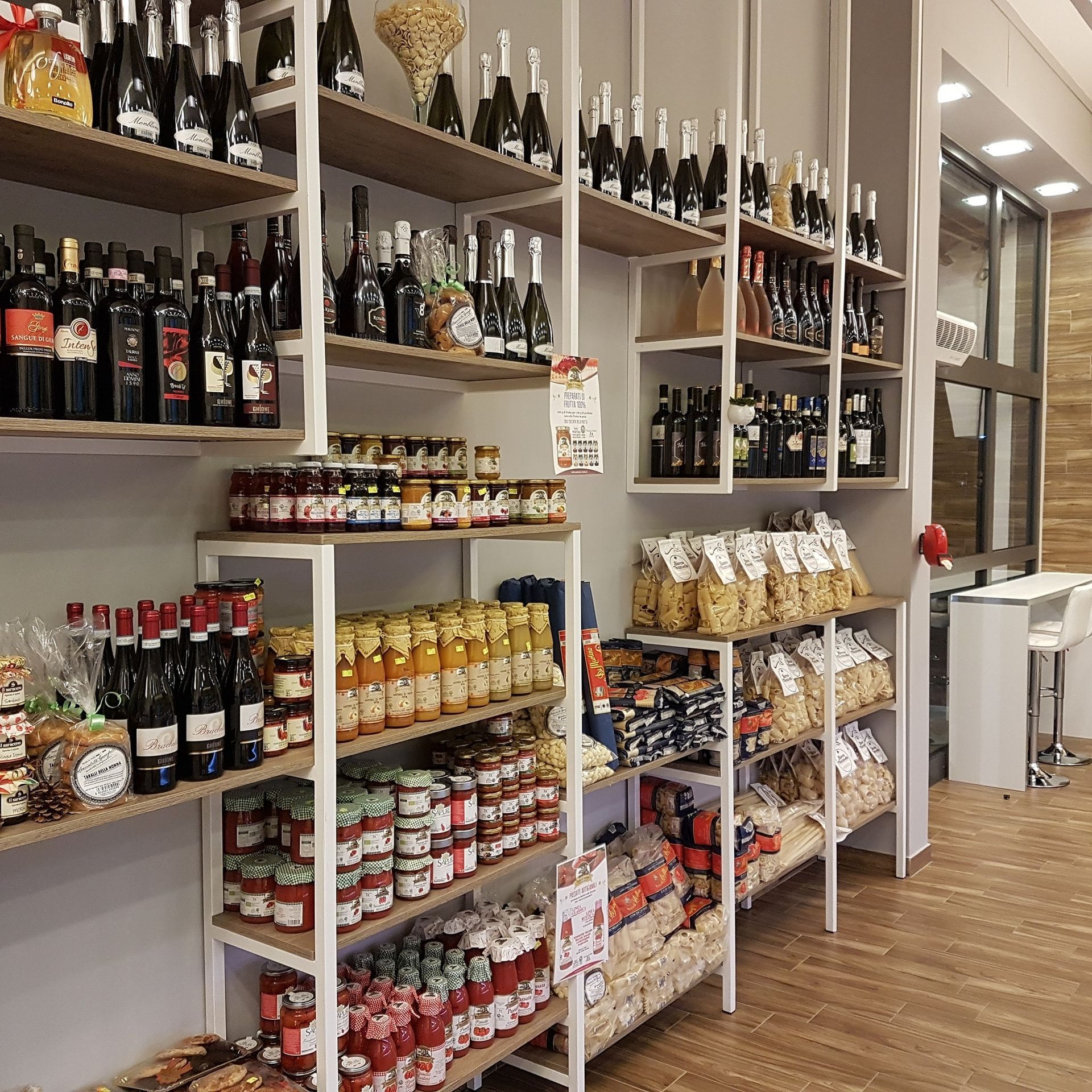 Scaffali pieni di barattoli di salse e bottiglie di vino in un negozio.