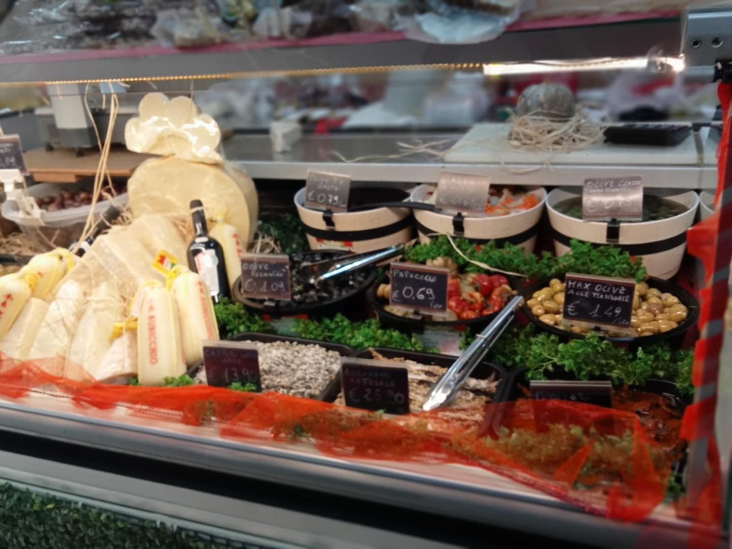 Vetrina con vari alimenti preparati, tra cui formaggi, olive e verdure sottaceto.