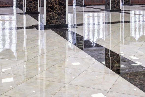 Shiny marble tiled floor with reflections of pillars and a window.