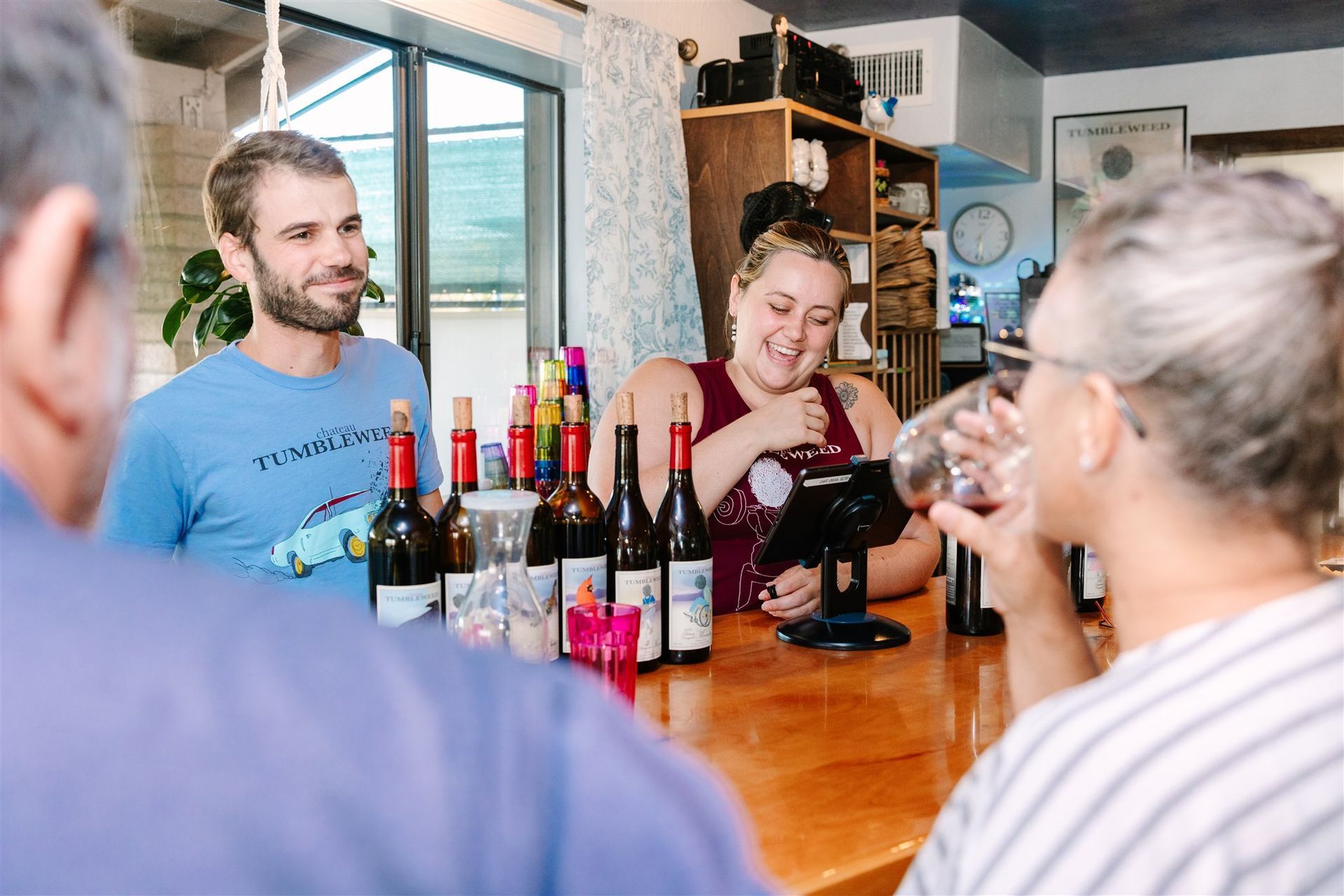 A group of people are sitting at a bar drinking wine.