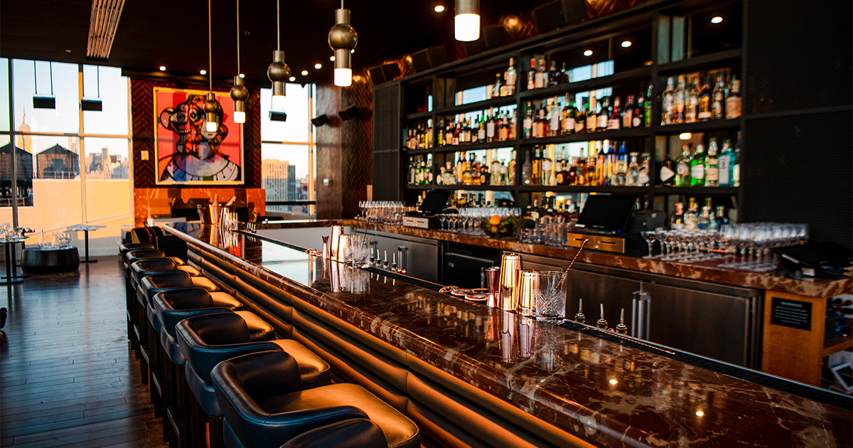 A long bar in a restaurant filled with lots of bottles of liquor.