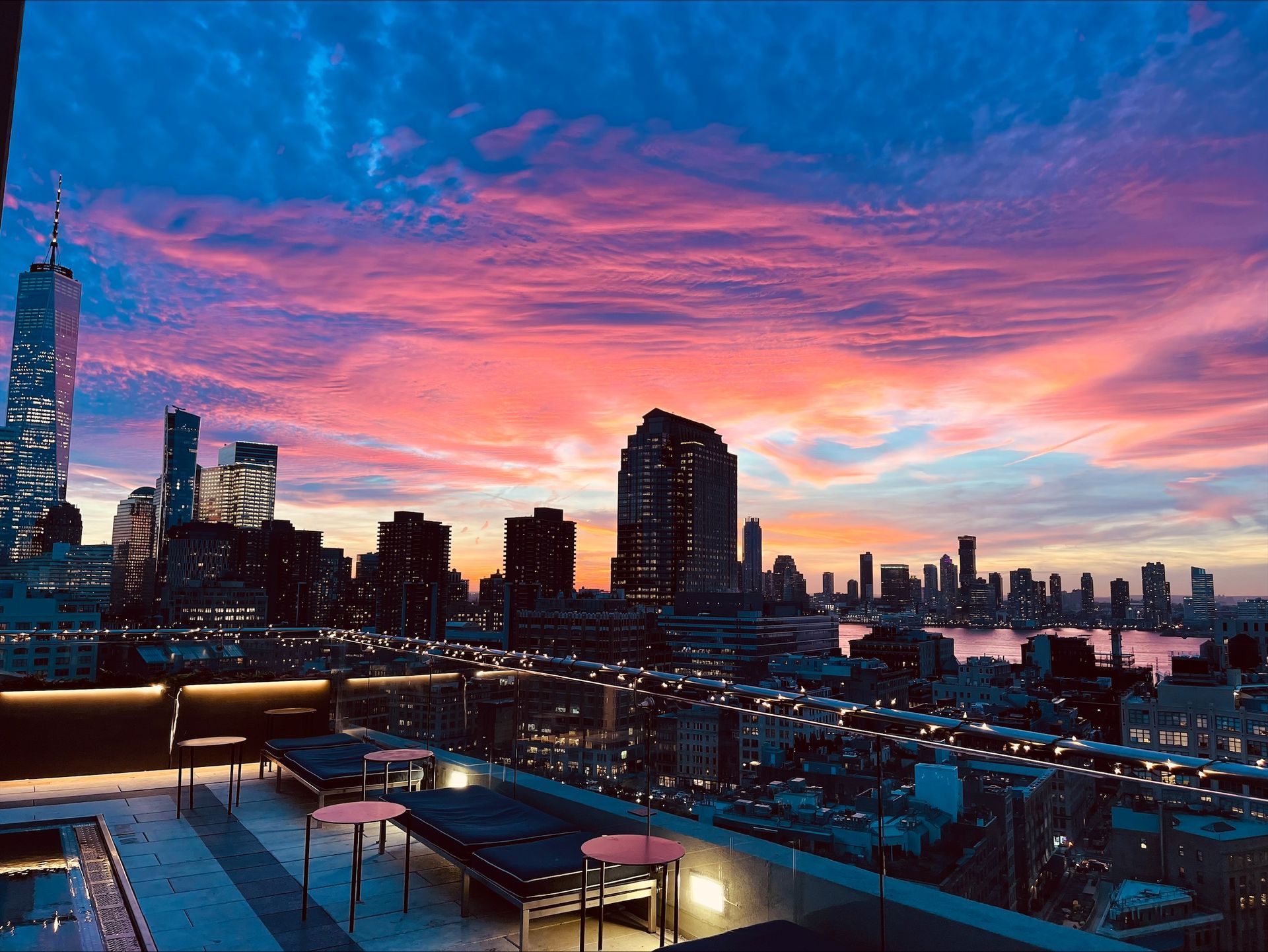 A sunset over a city skyline with a pool in the foreground.