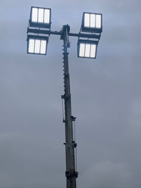 A tall pole with four lights on it against a cloudy sky.