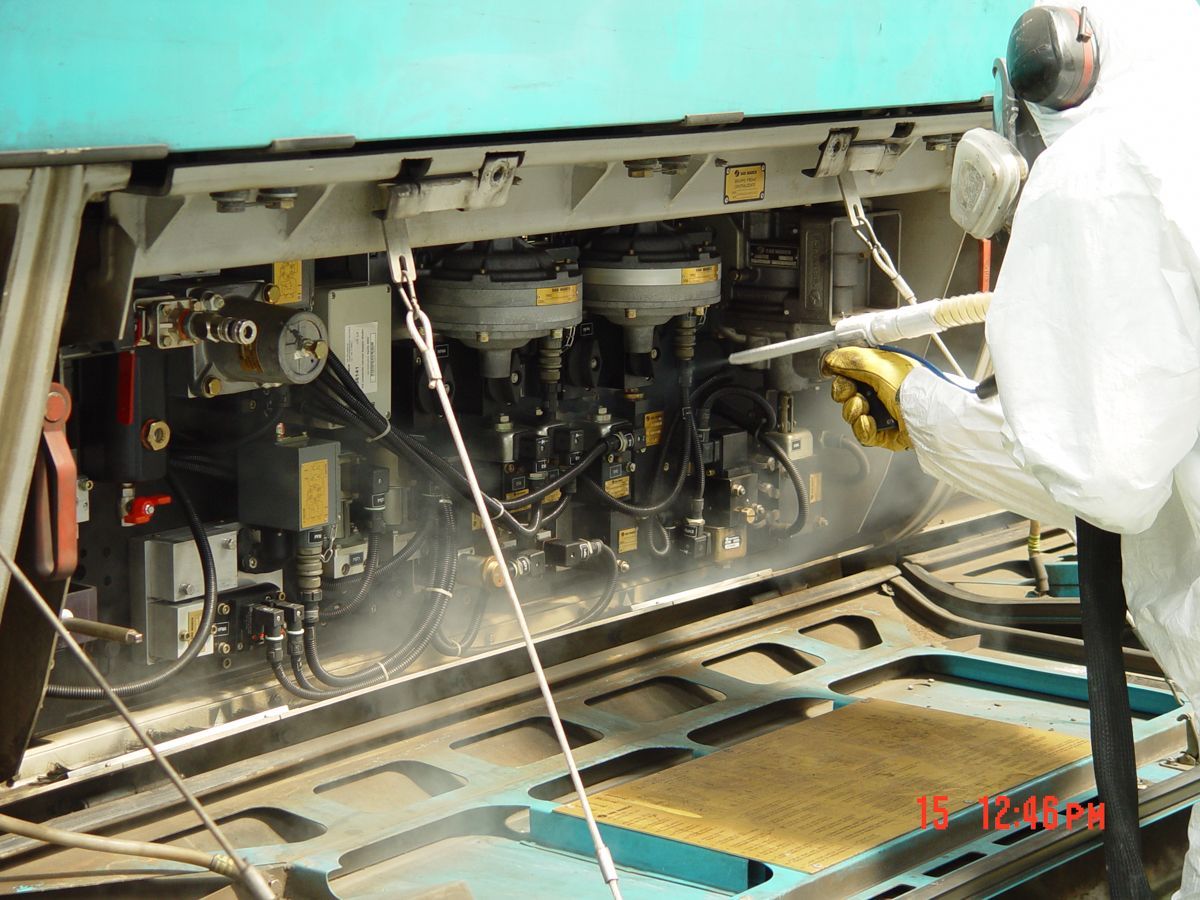 A man in a white suit is cleaning a machine