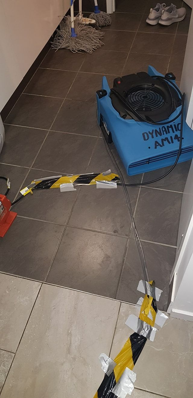 A Blue Machine is Sitting on a Tiled Floor Next to a Yellow and Black Tape — Dynamic Services in Yeppoon, QLD