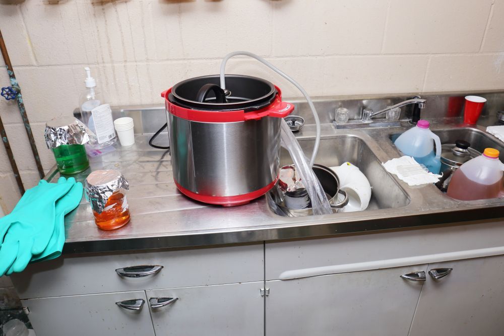 A Person Wearing Green Gloves is Cleaning a Kitchen Counter With a Pot on It — Dynamic Services in Limestone Creek, QLD