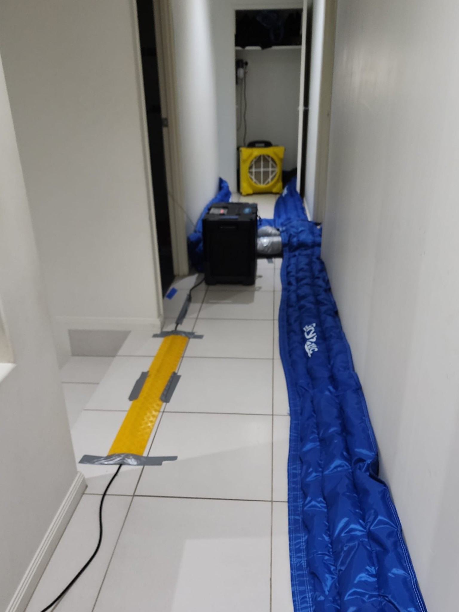 A Person Wearing Yellow Gloves is Cleaning a Wall With a Spray Bottle and a Sponge — Dynamic Services in Limestone Creek, QLD