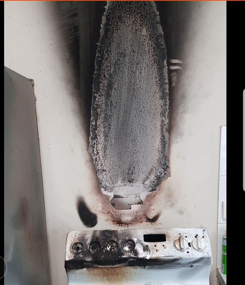 Charred stove with scorch marks on the wall above, indicating a kitchen fire.— Dynamic Services in Limestone Creek, QLD