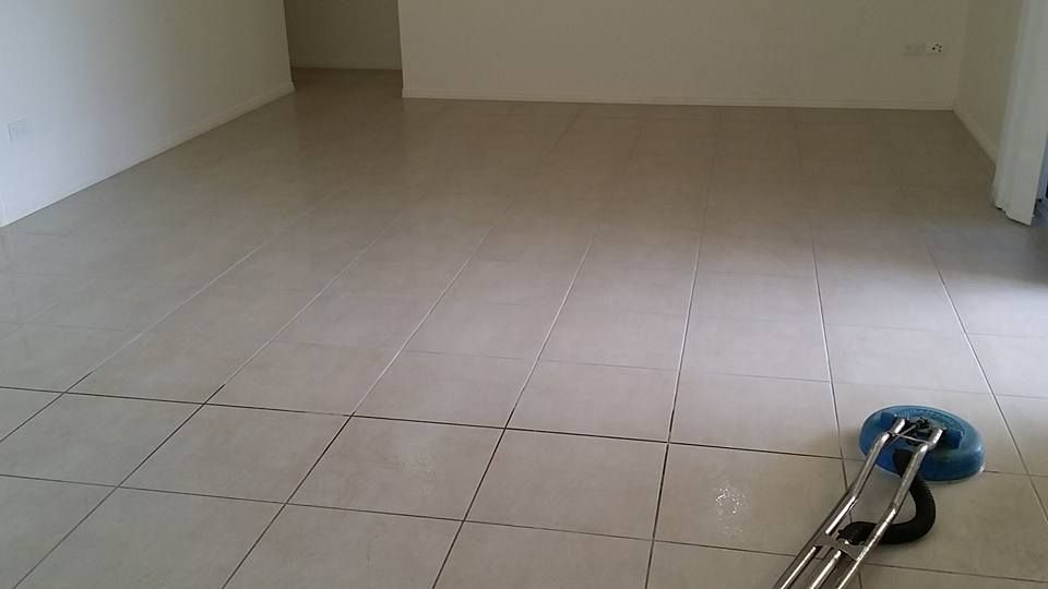 Light-colored tiled floor being cleaned with a floor buffer in an empty room.— Dynamic Services in Limestone Creek, QLD