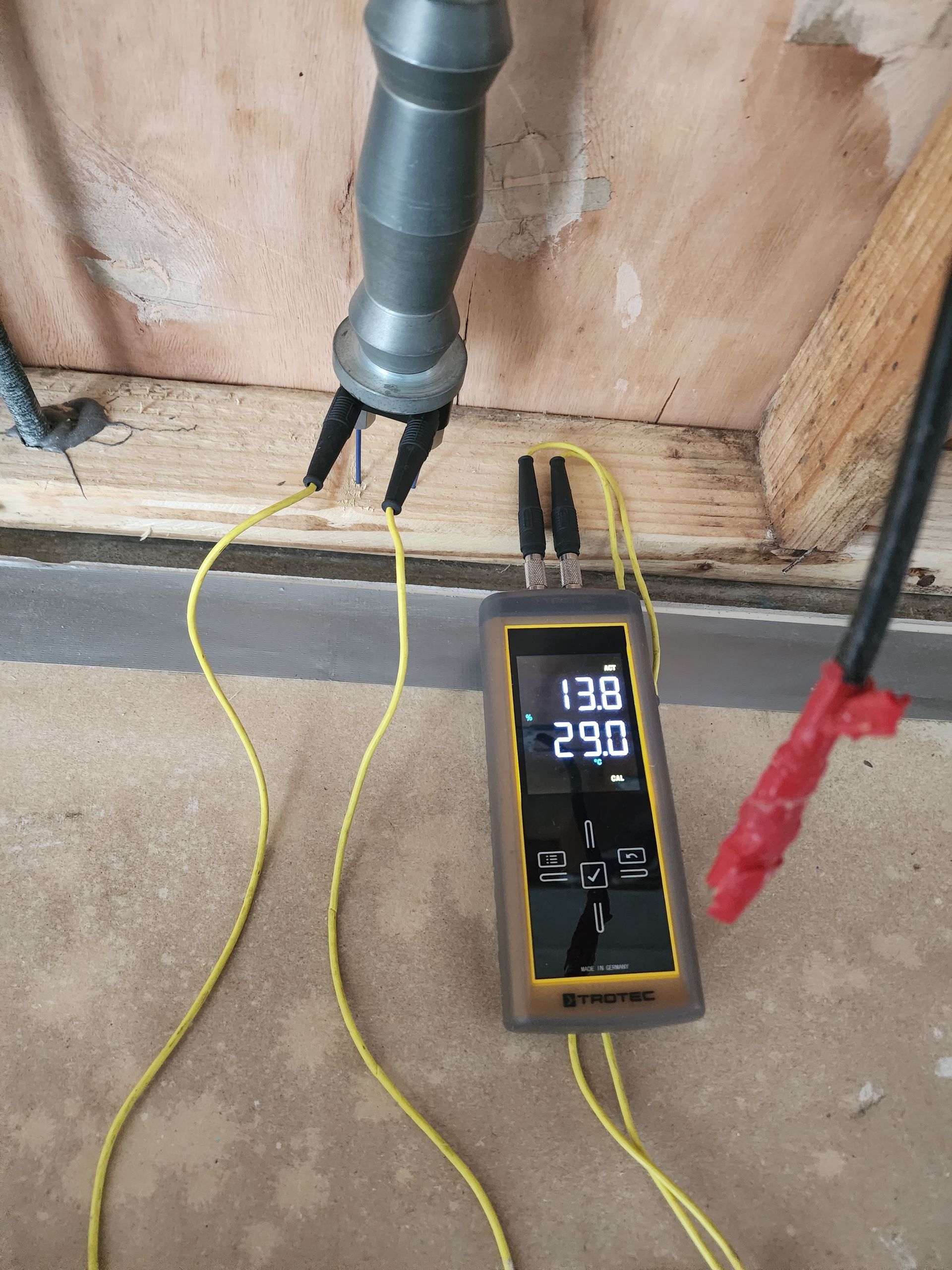 A digital temperature meter with probes measures 13.8 and 29.0 degrees, connected to a metal pipe in a room.— Dynamic Services in Limestone Creek, QLD