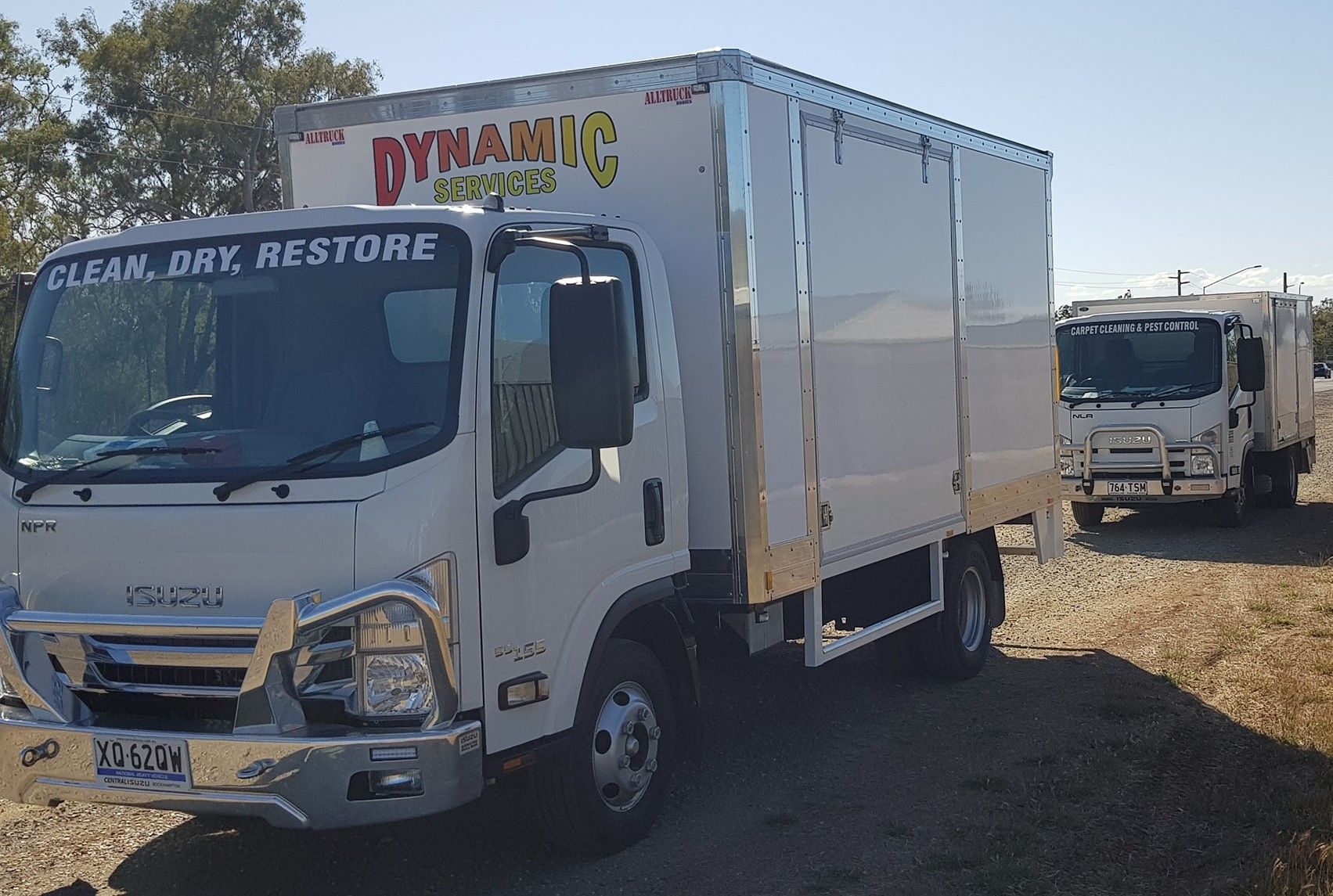 Two white Dynamic Storage trucks parked outside, one in front, on a sunny day.— Dynamic Services in Limestone Creek, QLD