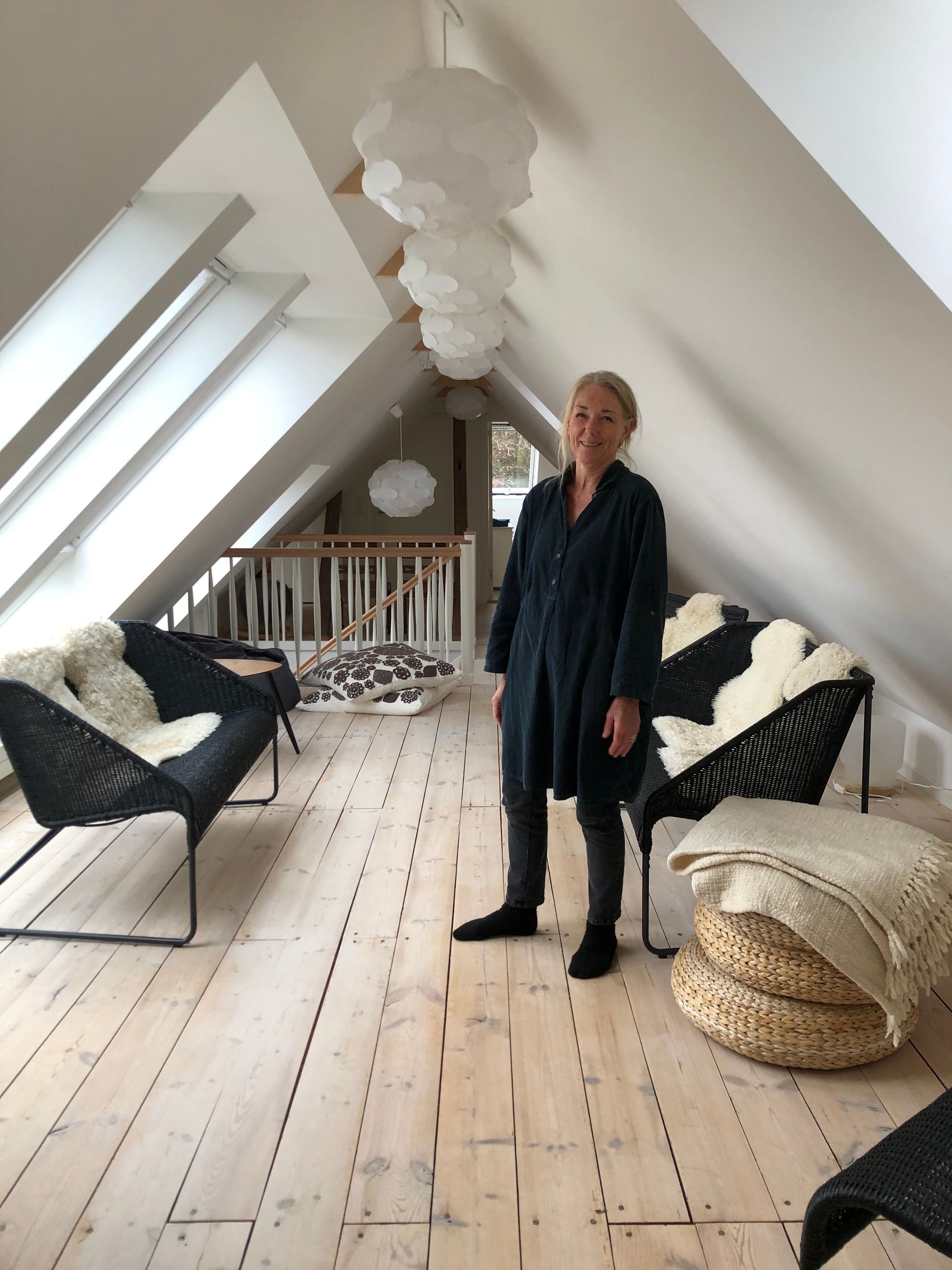 en kvinde står på et loft med stole og en sofa